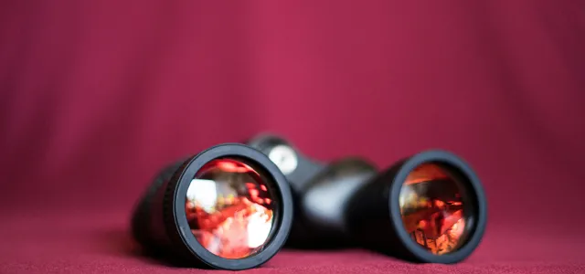 a pair of binoculars sitting on top of a red cloth by Kelli McClintock courtesy of Unsplash.